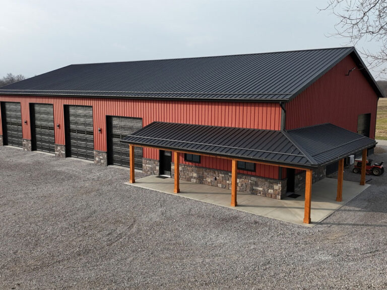 Home 39 Red barn construction with metal roof, garage doors, and covered entrance by Crockett Construction