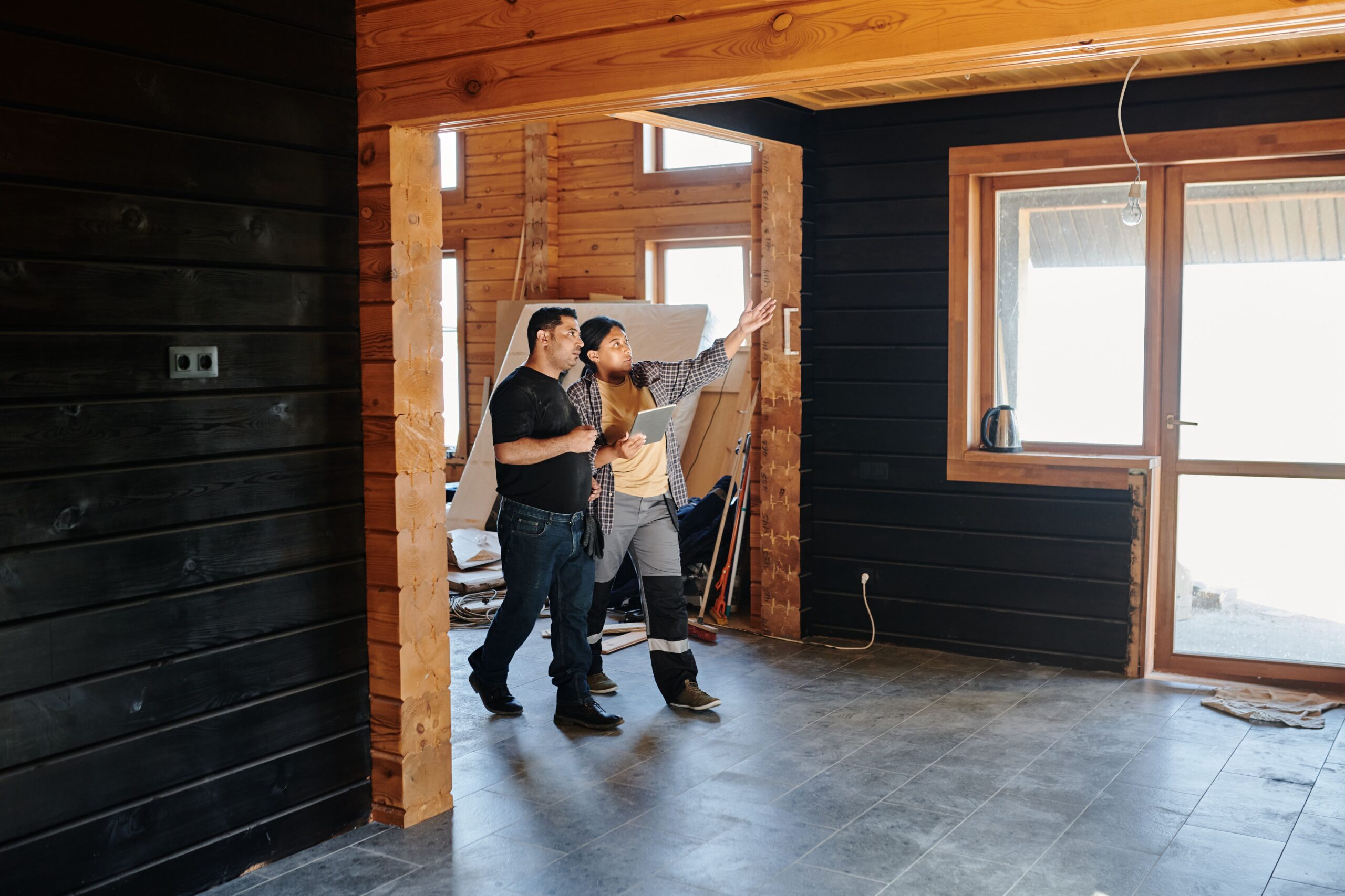Why June Is the Smart Month to Start Your Remodeling Project 2 Two adults discussing home renovation in a partially constructed modern wooden interior.